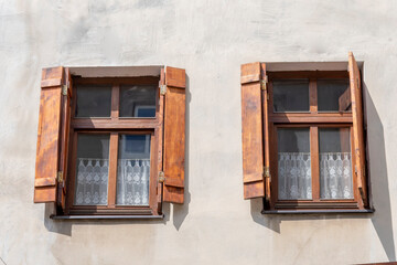 Two old windows with wooden frames and shutters, a fragment of the facade of an old building.
