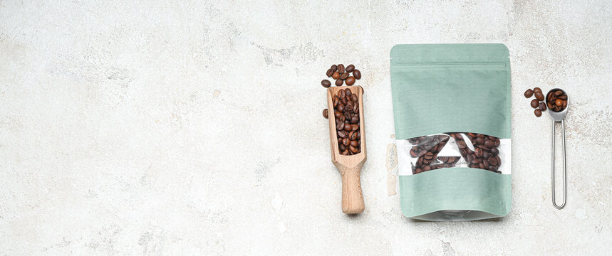 Coffee bag, scoop and spoon on light background with space for text