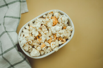 A small white bowl full of popcorn