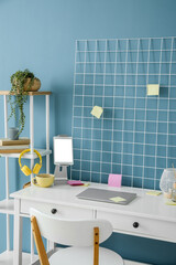 Modern workplace with laptop and tablet computer near blue wall