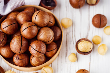 fresh macadamia nuts on a white wooden rustic background