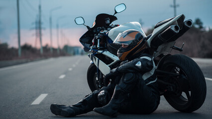 A motorcyclist is sitting on the road by a motorcycle