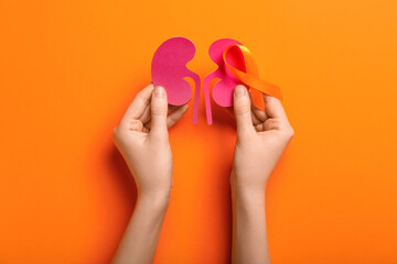 Woman with orange awareness ribbon and paper kidneys on color background