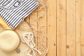 Clothes with hat, compass, rope and fish net on wooden background