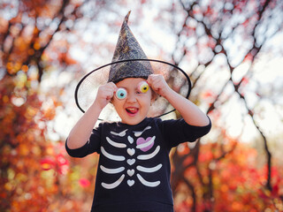Young girl in black costume goes trick or treating. Little witch, Kids with jack-o-lantern....