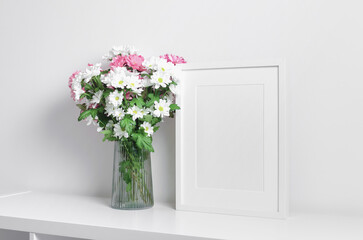 Portrait frame mockup in white minimalistic interior with fresh flowers bouquet