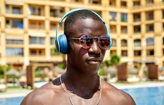 Black man listening to music near swimming pool