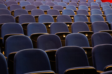 Close up shot of interior of cinema auditorium with lines of blue chairs. Horizontal shot