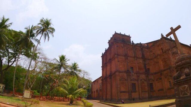 Closeup shot of Basilica of Bom Jesus Church and Crucifix Bom Jesus  in Goa, India. Cross of Jesus Christ in front of the old catholic church in Goa.  Basilica of bom Jesus besides the Palm trees