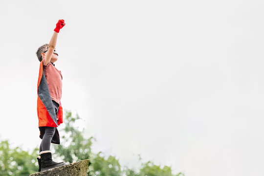 Superhero in hedgehog mask in park with arms raised with clenched fist