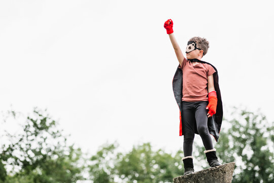 Superhero in hedgehog mask in park with arms raised with clenched fist