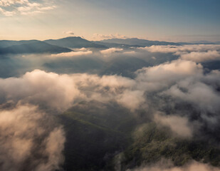 Fototapeta na wymiar Amazing aerial view of beautiful low clouds creeping on the tree-covered mountain slopes, the Rhodopes in Bulgaria at sunrise.