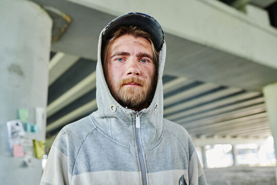 Portrait of homeless poor man with alcoholic bearded face looking at camera standing outdoors