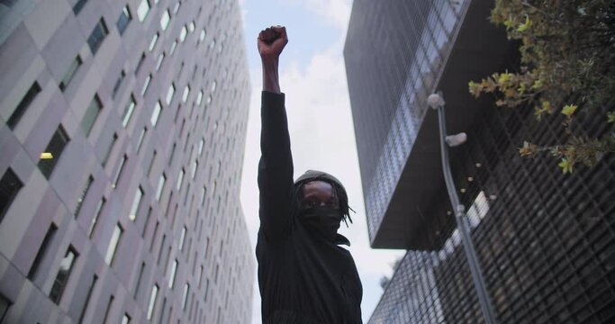 Young african american black man rasises his fists up in solidarity justice. 
