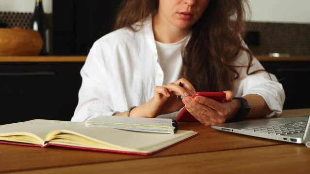 Accounting. Cropped young brunette woman using phone count amount payable on digital calculator, pay domestic bills fees online.Planning monthly budget at home office.Unsatisfied of increase in costs