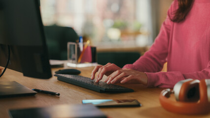 Close Up of a Female in Pink Jumper Working from Home on Desktop Computer. Student Making Homework...