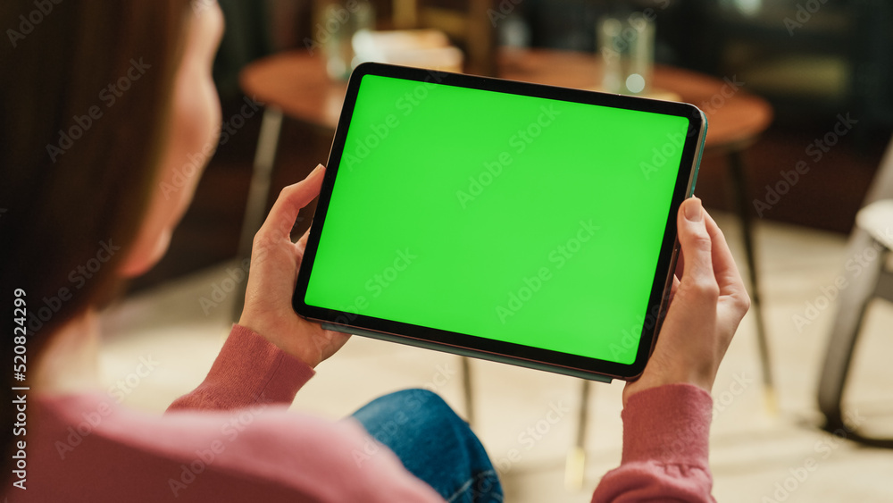 Poster female holding tablet computer with green screen mock up display. woman relaxing at home, watching v