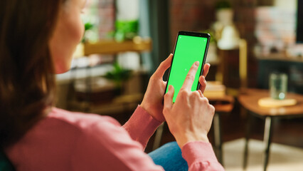 Feminine Hand Tapping on Display and Scrolling Feed on Smartphone with Green Screen Mock Up...