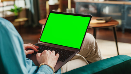 Young Adult Man Working from Home Loft Apartment on Laptop Computer with Green Screen Mock Up...