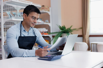 Entrepreneur male business owner in eyeglasses using computer laptop working in grocery shop store