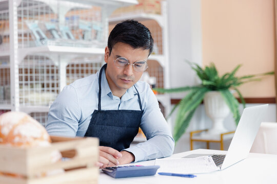 Entrepreneur male business owner in eyeglasses using computer laptop working in grocery shop store
