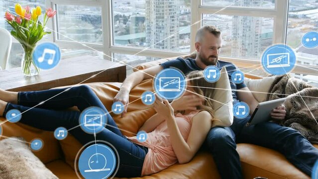 Animation of connections over caucasian couple lying on sofa with smartphone and tablet