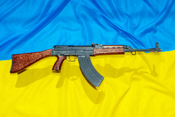 The old assault rifle above the Ukrainian flag symbolizes resistance against the aggressor