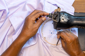 Embroidering Thai numbers on a student's shirt on an old sewing machine