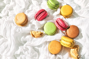 Colorful french macarons on white textile. Tasty cake macaroon of different colors. Almond cookies, pastel colors.