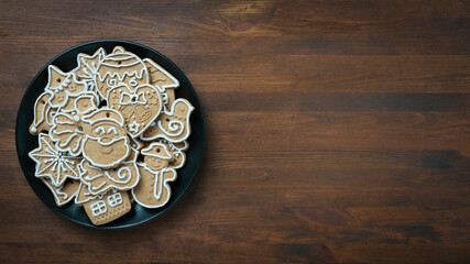 Christmas gingerbread cookies on a dark plate on a wooden background with copy space