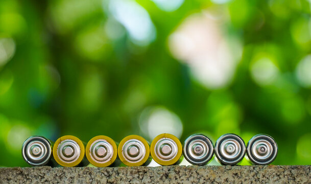 disposable alcaline batteries against natural green bokeh background, type AA