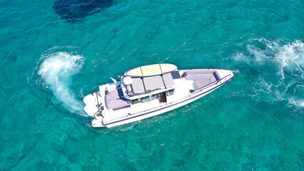 Aerial drone photo of small speed boat with dual outboards cruising in low speed deep turquoise Aegean sea