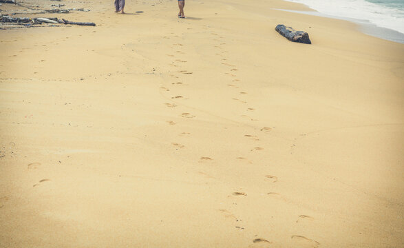 People Walk on the Beach. Travel Vacation Retirement Lifestyle Beach travel Concept. Traveler walking on sand beach leaving footprints in the sand.