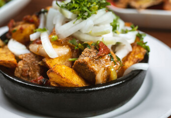 Beef stew with potatoes, carrots and herbs on black background with copy