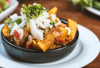 Beef stew with potatoes, carrots and herbs on black background with copy