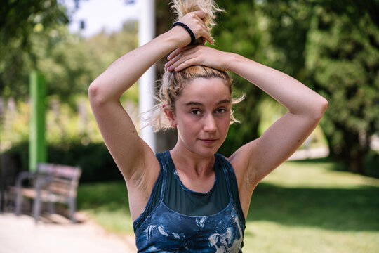 Blonde young woman determined athlete putting her hair up in a ponytail