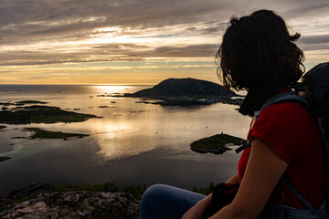 a woman observes midnight sun from Ornfloya Hiking Trail at Sommaroy (Sommarøy), Tromso Norway