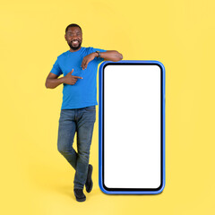 African American Guy Leaning On Large Smartphone Screen, Yellow Background