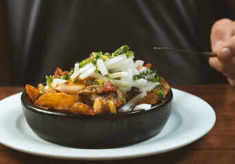 Man eating Beef stew with potatoes, carrots and herbs on black background with copy