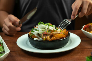 Man eating Beef stew with potatoes, carrots and herbs on black background with copy