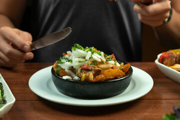 Man eating Beef stew with potatoes, carrots and herbs on black background with copy