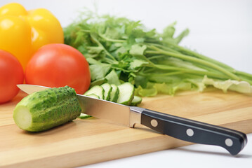 Chopping board with tomato, cucumber, parsley and knife
