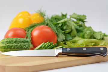 Chopping board with tomato, cucumber, parsley and knife