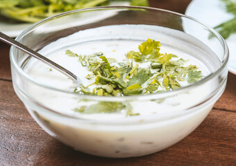 yogurt soup with herbs in a plate on a wooden table.spas