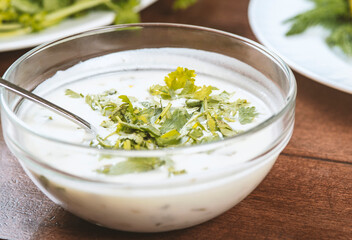 yogurt soup with herbs in a plate on a wooden table.spas