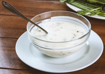 yogurt soup with herbs in a plate on a wooden table.spas
