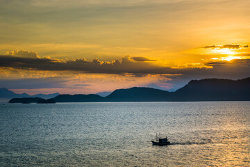 Naklejka na ściany i meble Sunset over the sea with a fishing boat at Angra dos Reis town, State of Rio de Janeiro, Brazil. Taken with Nikon D7100 18-200lens, at 46mm, 1/160 f 8.0 ISO 100. Date: Dec 27, 2016