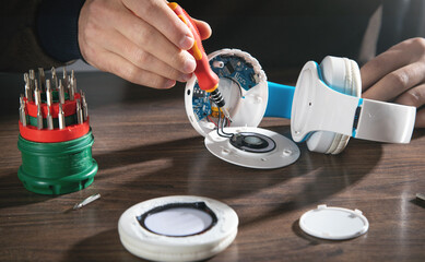 Man repairing white wireless headphones.