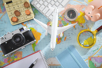 Fototapeta na wymiar Calculator, coins, retro camera, airplane on the world map.