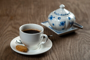 a cup of coffee with cookies and a sugar bowl on the table